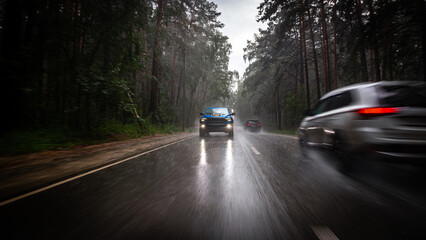 a blue new pickup truck is driving along a highway in the forest, with blurred cars