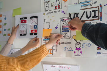 Image of a team of developers brainstorming UI and UX design ideas for a mobile app on a paper...