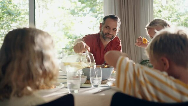 Video of beautiful family talking while eating together in the kitchen at home