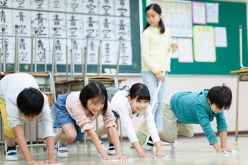 教室の床を雑巾がけする小学生たち