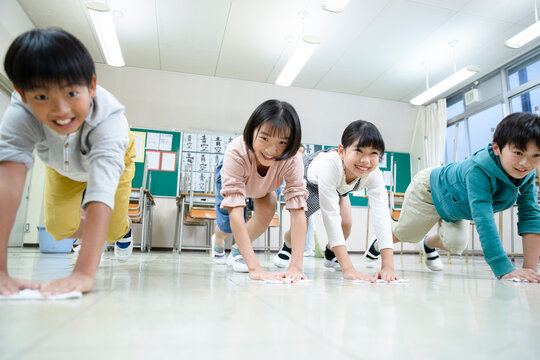 教室の床を雑巾がけする小学生たち