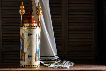 Torah scroll with prayer shawl tallit and kippah on a dark background
