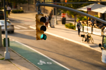 Green traffic light showing that is allowed to cross the street with a green bike lane in frame. Transportation industry in America.