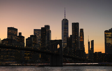 Fototapeta premium Landscape in Manhattan. The silhouettes of modern skyscraper office buildings from New York during a beautiful summer sunset. Travel to America.