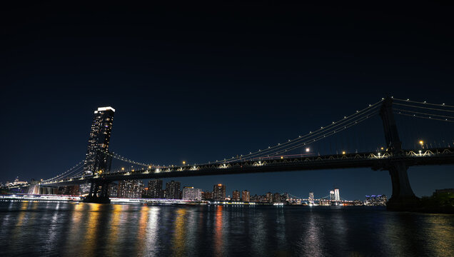 New York skyline by night. Landscape photo during the evening, view to Brooklyn and Manhattan bridge and landmark skyscraper office buildings from New York, America.