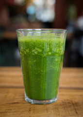 Homemade fresh green smoothie in a glass on a wooden table in a café restaurant