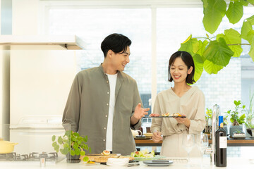 キッチンで料理を楽しむ30代夫婦