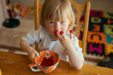 child eats fruit. I put a raspberry on my finger. child plays with food.