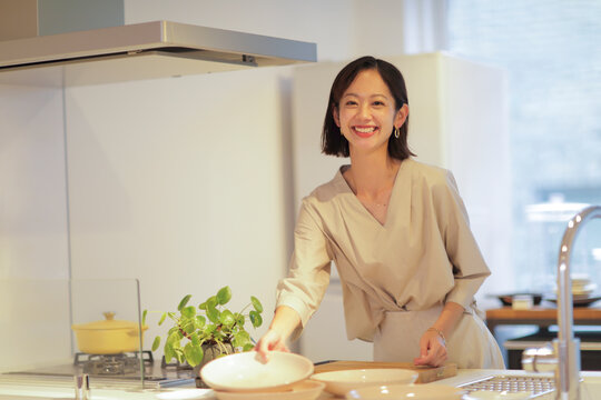 キッチンで食器を片付ける30代女性