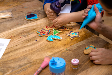 Christmas cookies workshop. Children decorating cookies with colorful pastry bags.