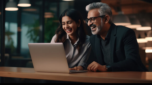 Senior Businessman And His Female Assistant Laughing While Looking In Laptop