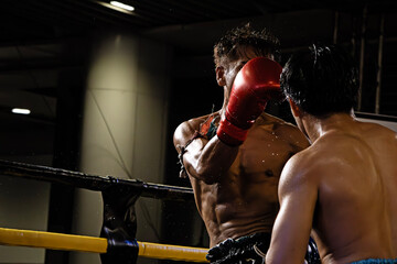 Thai boxing, martial art Muay Thai, two athletes in the ring, blue and red gloves, photo taken at the moment of impact.