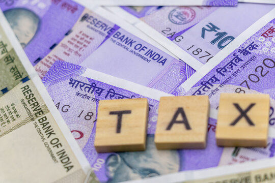Close up shot of money with defocused tax word on wood chips.