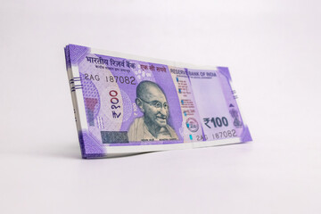 New Indian currency of 100 rupee notes against white background.
