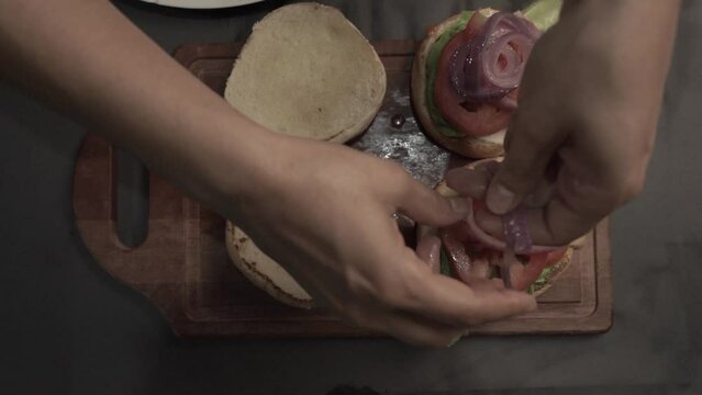 MANO COLOCANDO CEBOLLA EN HAMBURGUESA