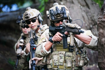 Military army soldiers tactical team, commando group moving cautiously in forest area, kneeling and looking around, covering comrades, controlling sectors. Commander showing halt or stop hand signal
