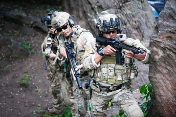 Military army soldiers tactical team, commando group moving cautiously in forest area, kneeling and looking around, covering comrades, controlling sectors. Commander showing halt or stop hand signal