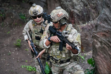 Fototapeta premium Military army soldiers tactical team, commando group moving cautiously in forest area, kneeling and looking around, covering comrades, controlling sectors. Commander showing halt or stop hand signal