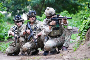 Military army soldiers tactical team, commando group moving cautiously in forest area, kneeling and...