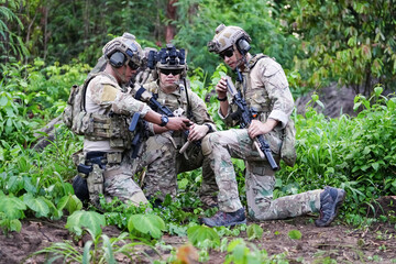 Fototapeta premium Military army soldiers tactical team, commando group moving cautiously in forest area, kneeling and looking around, covering comrades, controlling sectors. Commander showing halt or stop hand signal