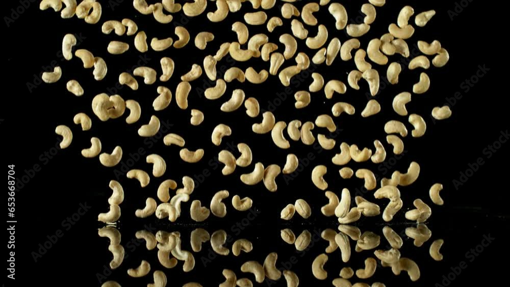 Poster super slow motion of falling cashew nuts with reflection. isolated on black background. filmed on hi