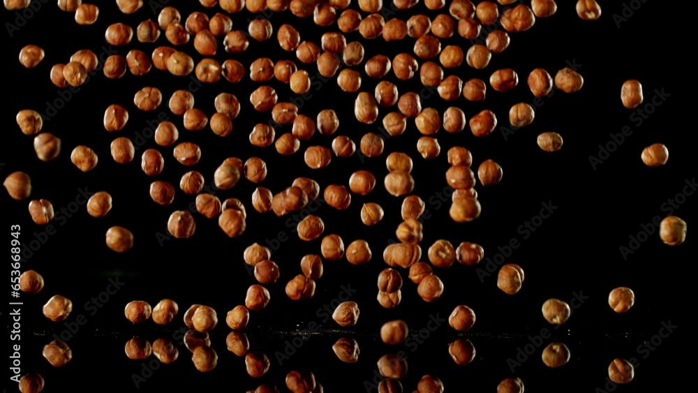 Poster super slow motion of falling hazelnuts with reflection. isolated on black background. filmed on high