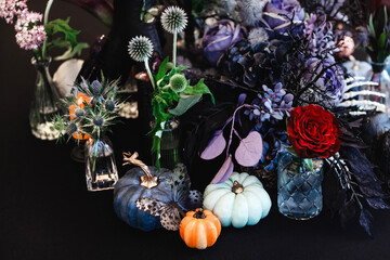 Autumn table composition with three colourful pumpkins and plants in dark purple tones. The theme of the holiday Halloween.