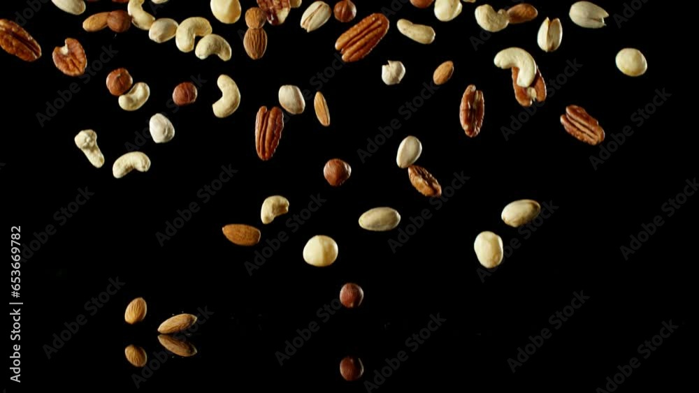 Poster super slow motion of falling mix nuts with reflection. isolated on black background. filmed on high 