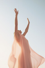 An Indian woman in a traditional gown with outstretched arms under the sunlight, representing spirituality. - 653671165