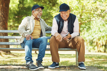 Senior friends, funny and relax at park, talking and bonding outdoor in retirement. Happy elderly men sitting together in garden on bench, communication and laughing at comedy, joke or meme on phone