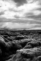 View of pristine volcanic landscape in the highlands in the south of Iceland at midsummer on a cloudy day. Moss covered lava rocks and dramatic cloudy sky. Black and white scenery. Remote place.