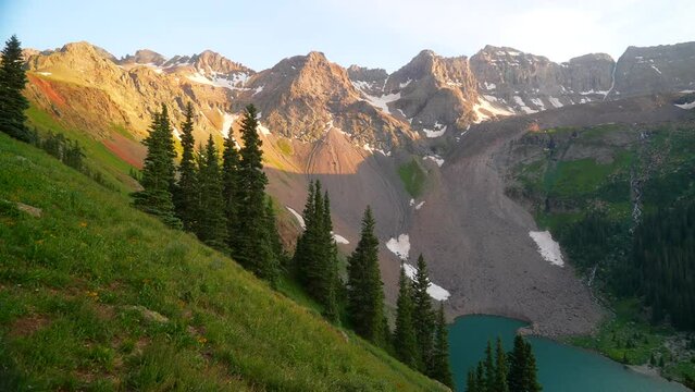 Yellow wild flowers Mount Sniffels Peaks Wilderness Upper Blue Lake Colorado summer snow melting top of Rocky Mountain stunning golden hour sunset Silverton Telluride 14er cinematic slow pan right
