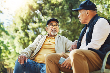 Elderly friends, men and relax at park bench, talk and bonding outdoor with phone. Senior people sitting together in garden, communication and serious conversation in nature for retirement in spring - obrazy, fototapety, plakaty