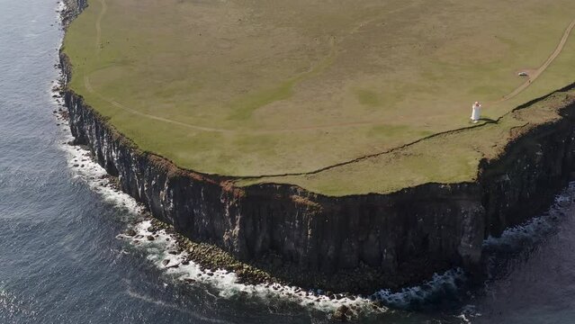 Aerial top down shot of Lighthouse at edge of cliff in Langanes Island, Iceland - tilt up shot