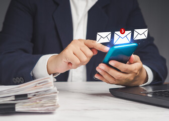 Businesswoman using a smartphone receives a new message with email icons while sitting at the table
