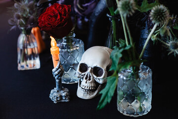 Halloween table arrangement with skull, candle, rose and thorny plants in a dark colour scheme.