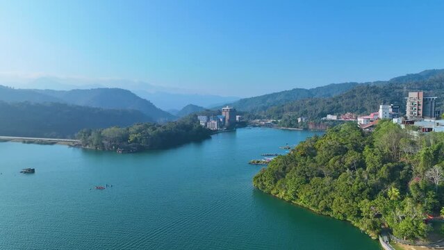 Scenic Sun Moon Lake on a foggy autumn evening: wooden piers extend into the misty water, surrounded by colorful foliage and lakeside hotels in Nantou National Park, Taiwan.