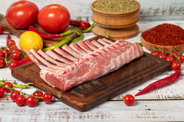 Lamb rack cutlet on wood background. Raw lamb chops with herbs and spices
