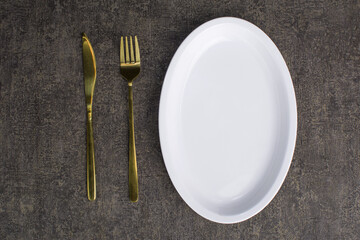 gold cutlery, forks, knives and white plates. placed on wood