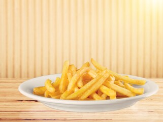Plate of tasty hot French fries on the desk