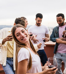 Beautiful carefree blonde girl dancing in a rooftop party.Young cheerful lady having fun in a terrace with a glass of wine.