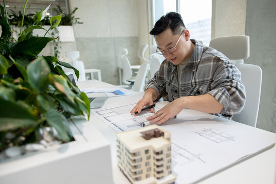 Man architect working with blueprints modeling modern house.