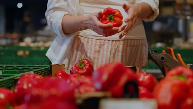 A woman consumer chooses vegetables on the shelves of a store in a shopping center. Choosing and buying food home fresh vegetables and fruits on store shelves in a shopping center