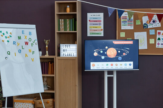 Background image of learning materials in preschool room interior with whiteboard and space theme digital screen, copy space
