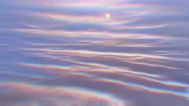 Blurred water slowly moving. Ripples with chromatic aberration and glistening reflections.