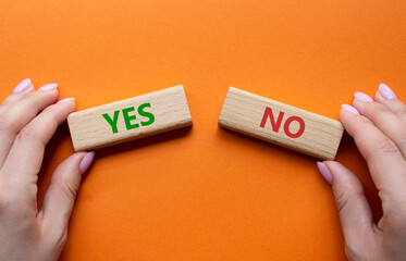 Yes or No symbol. Concept word Yes or No on wooden blocks. Businessman hand. Beautiful orange background. Business and Yes or No concept. Copy space