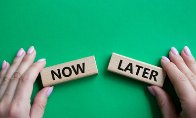 Now vs Later symbol. Concept word Now vs Later on wooden blocks. Businessman hand. Beautiful green background. Business and Now vs Later concept. Copy space
