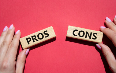 Pros vs Cons symbol. Concept word Pros vs Cons on wooden blocks. Businessman hand. Beautiful red background. Business and Pros vs Cons concept. Copy space