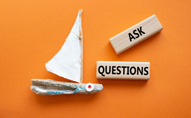 Ask Questions symbol. Wooden blocks with words Ask Questions. Beautiful orange background with...