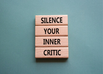 Silence your inner critic symbol. Wooden blocks with words Silence your inner critic. Beautiful grey green background. Businessman hand. Business and Silence your inner critic concept. Copy space.